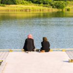 Two people sitting peacefully on a dock.