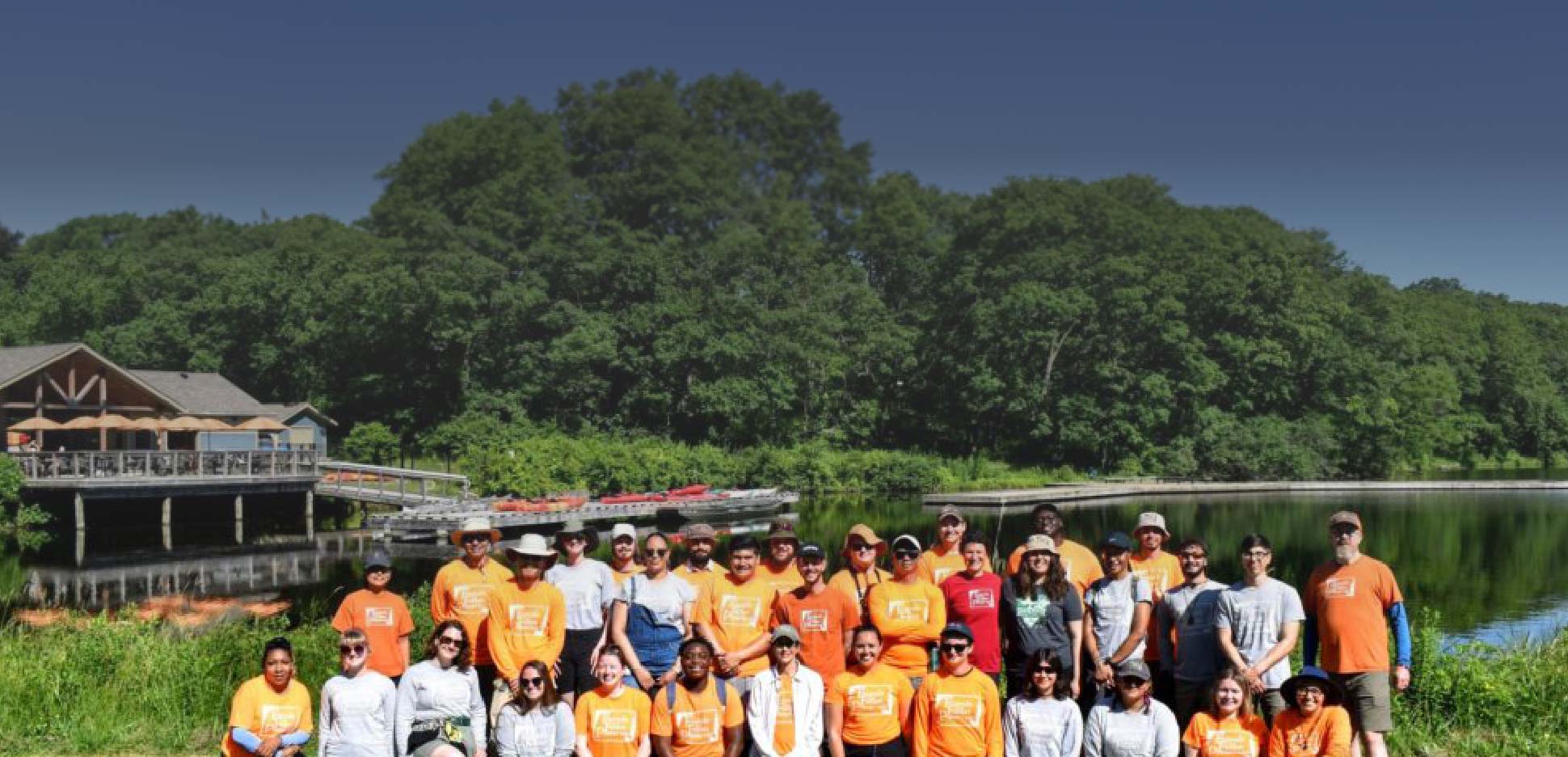 Group photo of staff in front of a lake and facility