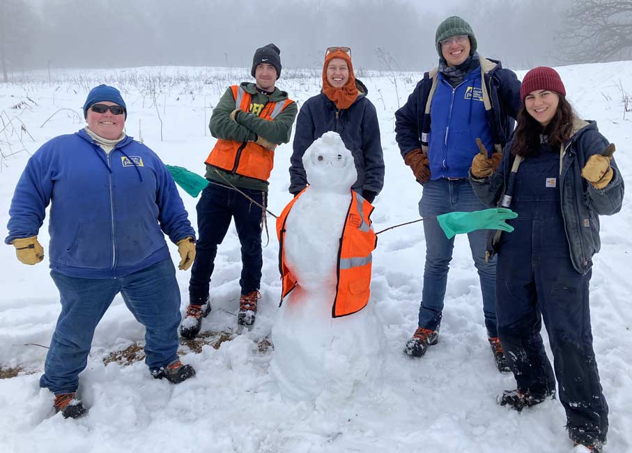 Volunteers posing with a snowman photograph